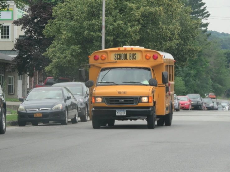 school bus with driver stopped behind cars on city street