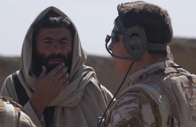 a man in headphones talks to an afghan soldier