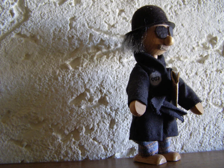 a wooden toy is dressed in clothing and holding a cane