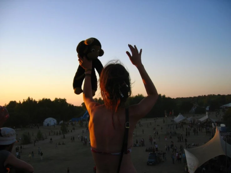 a person holds up a teddy bear above her head