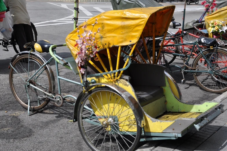 a yellow rickshaw with a covered wagon parked by two bicycles