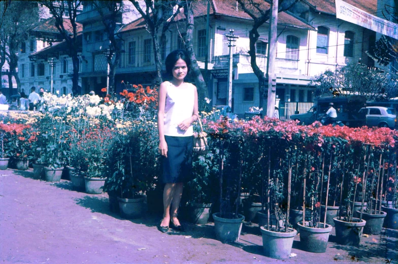 a woman is standing near some pretty flowers