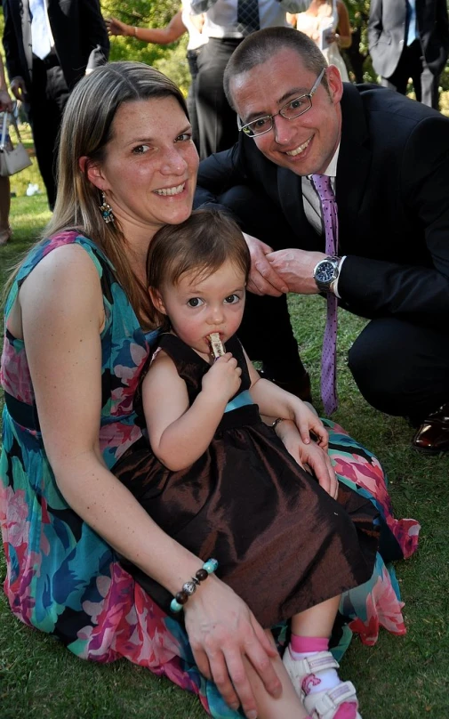 a man kneeling next to a woman holding a little girl