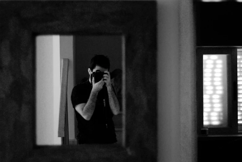 man taking a picture with his digital camera in a mirror