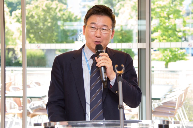 a man wearing glasses standing at a podium talking