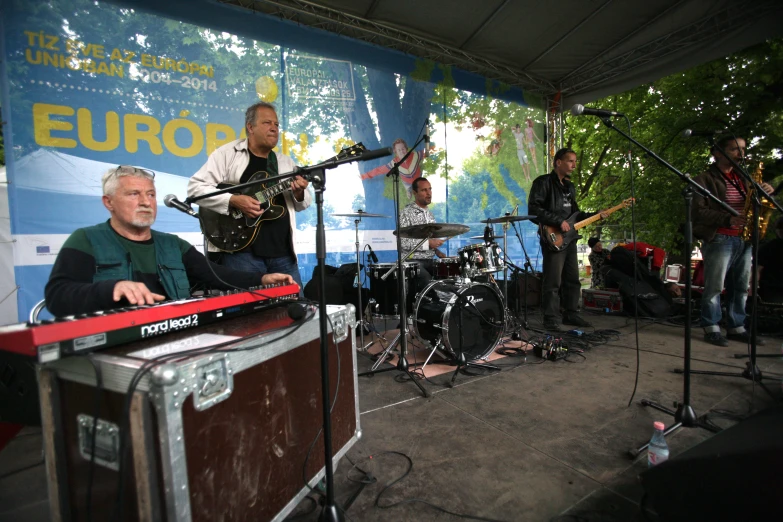 people singing and playing musical on stage at outdoor event