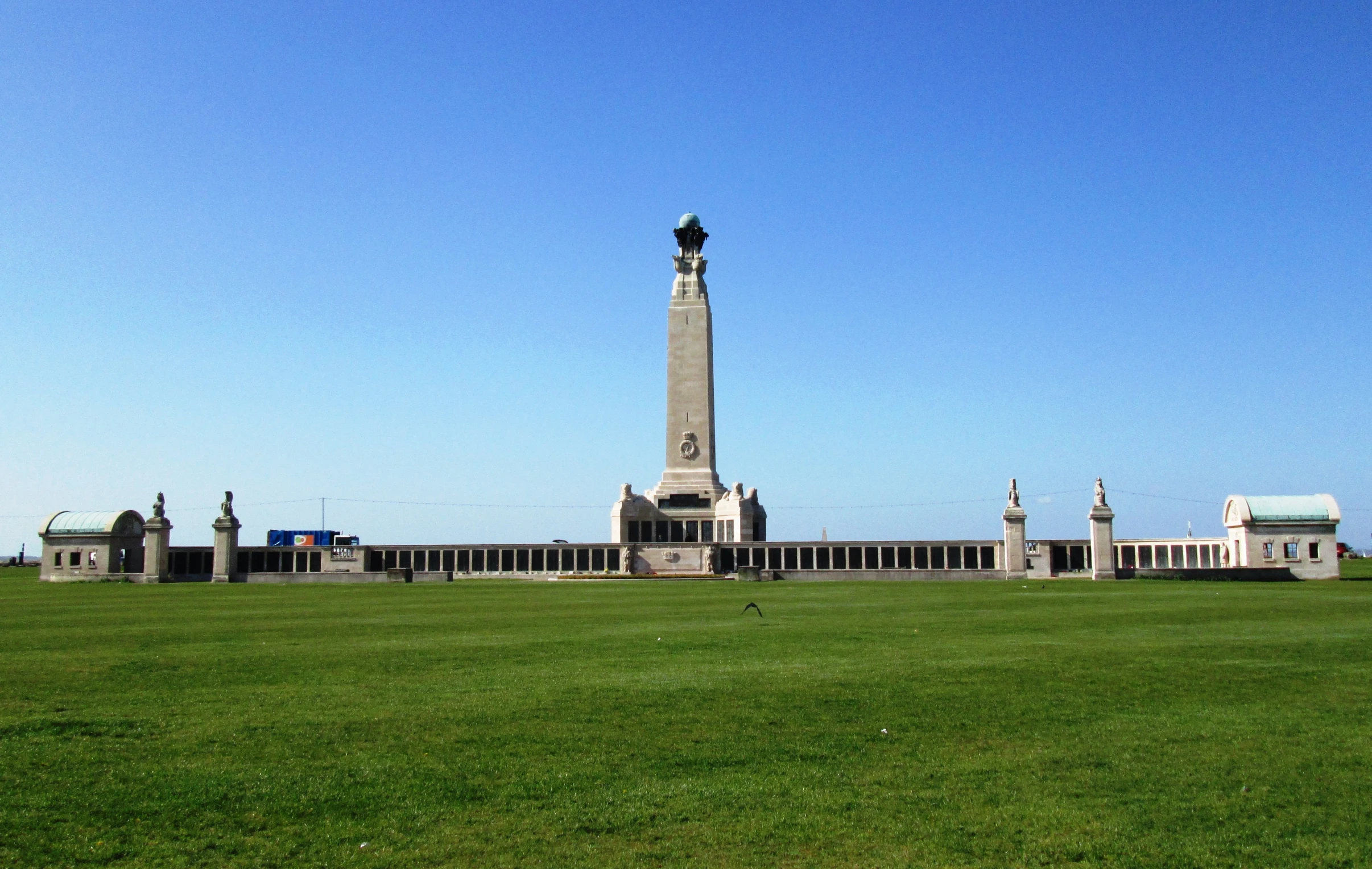 an obelisk in the foreground is a building in the background