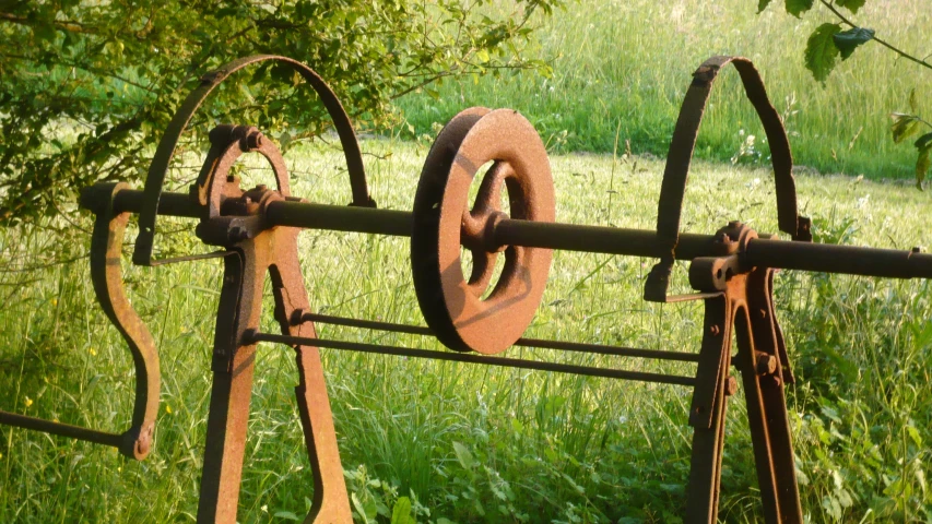 an image of old rusty farm tools on the green grass