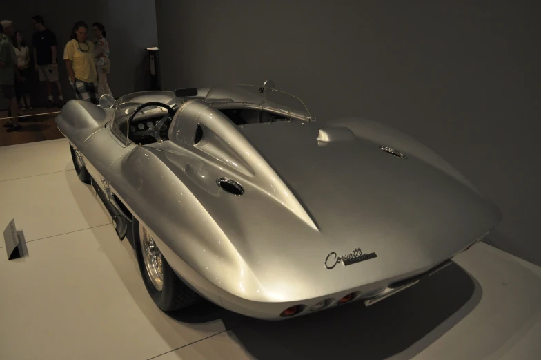 a vintage silver car with a small top in a room