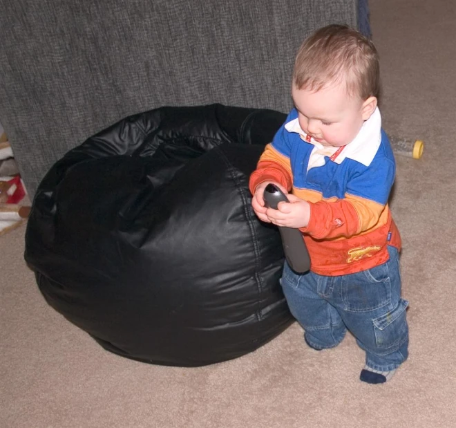 a toddler with a remote on his hands looking at a bag
