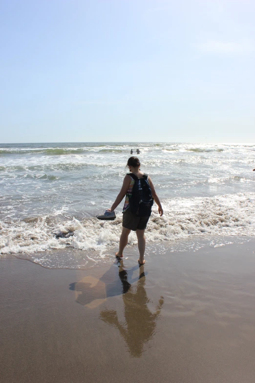 a woman walking on top of a beach near the ocean