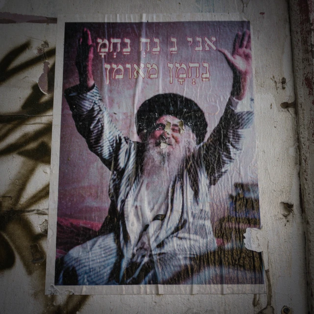 a religious print with an old, worn out poster on the wall