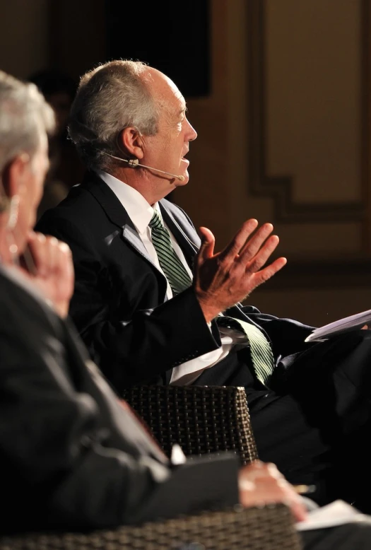 a man sitting in a chair while talking to other people