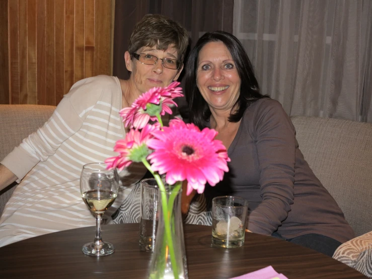 two women are sitting at a table with wine