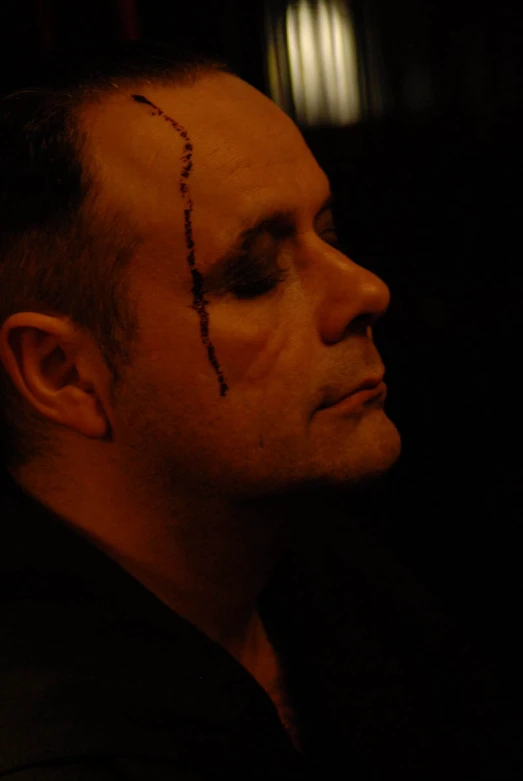 a man with cross on his forehead stares off into the distance