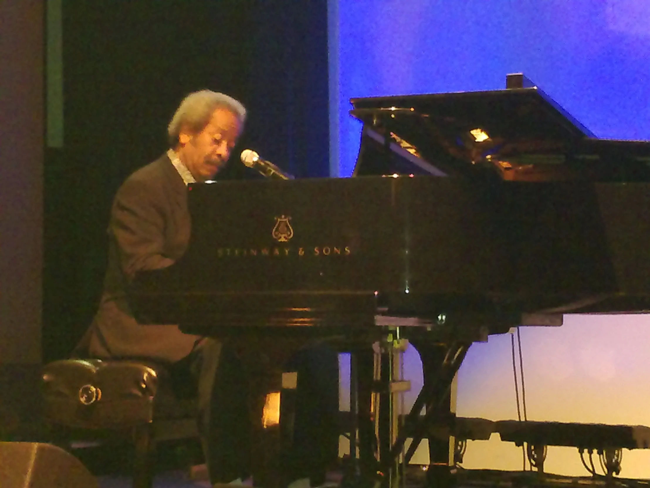 a man sitting at a piano with a microphone