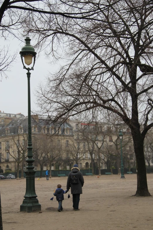 two people walking on the street by a lamp post with trees