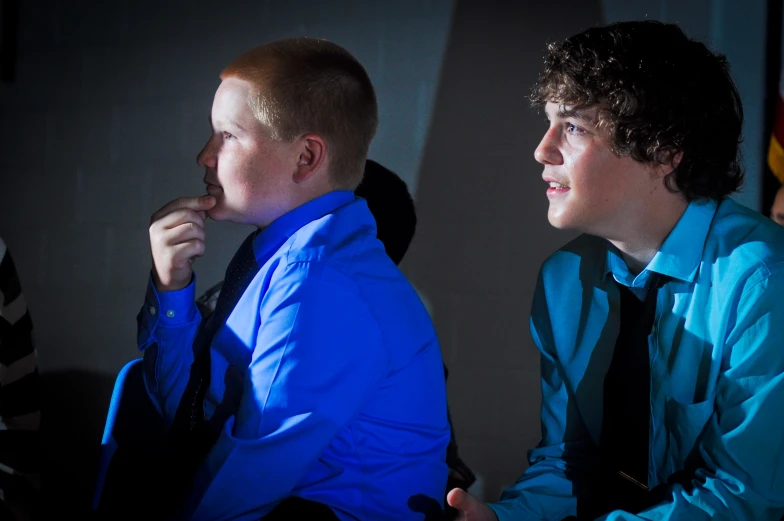 a couple of young men sitting next to each other