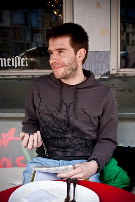 a man is eating dinner outside with his hands on his knees