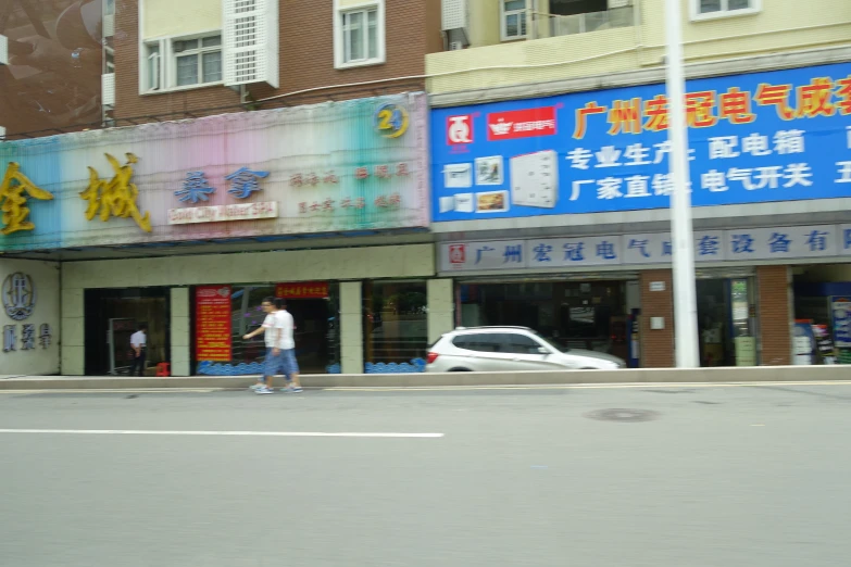 a man walking down the street past a chinese store