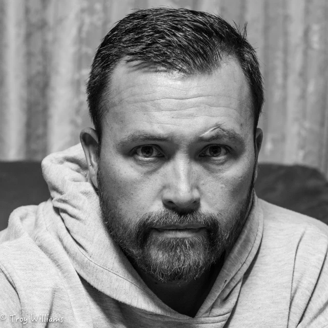 the man is posing for a portrait while wearing a hoodie