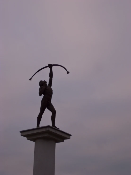 a bronze statue stands in front of a purple sky