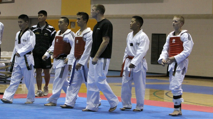 several people on a blue mat with white pants