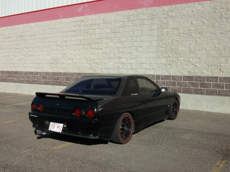 a black car in front of a brick wall