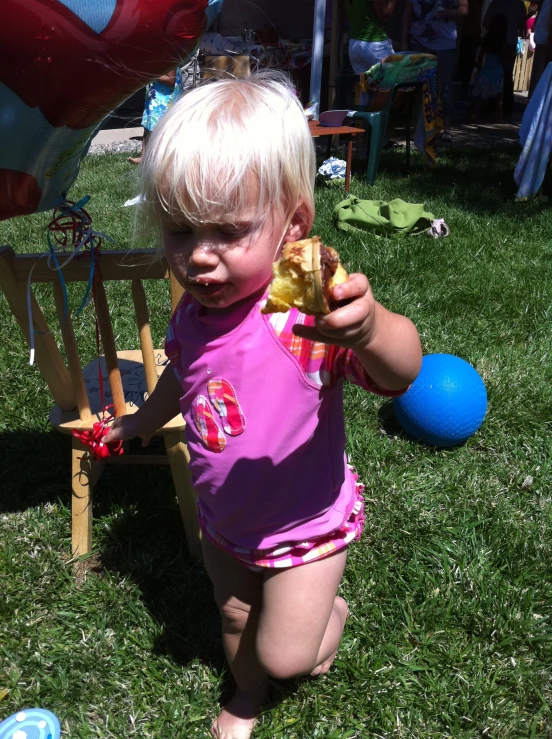 baby on the ground eating a cookie in the backyard