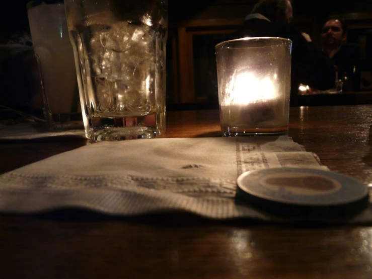 a plate sitting on top of a wooden table next to a glass and candles