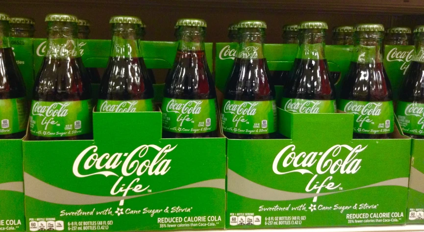 green and red bottles of soda are on the shelves