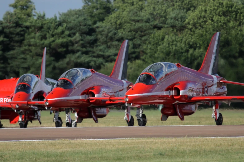 a bunch of red planes that are on a runway