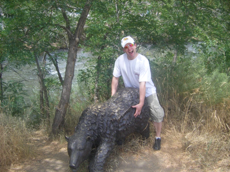 a man wearing a white cap poses with a large animal