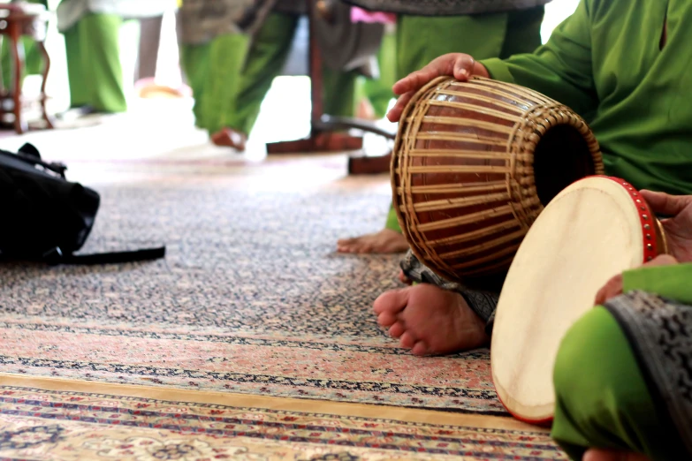 a person holding a wooden instrument sitting on a carpet