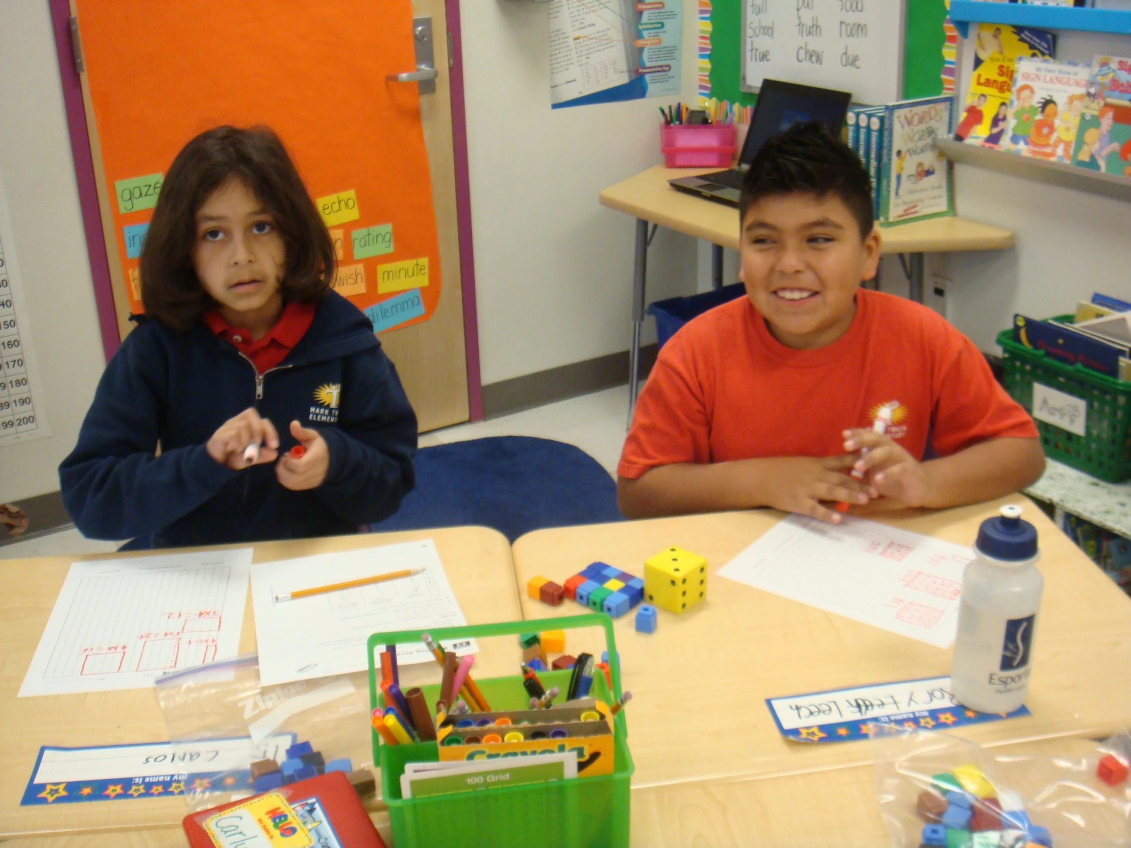 two young children sitting at a desk together