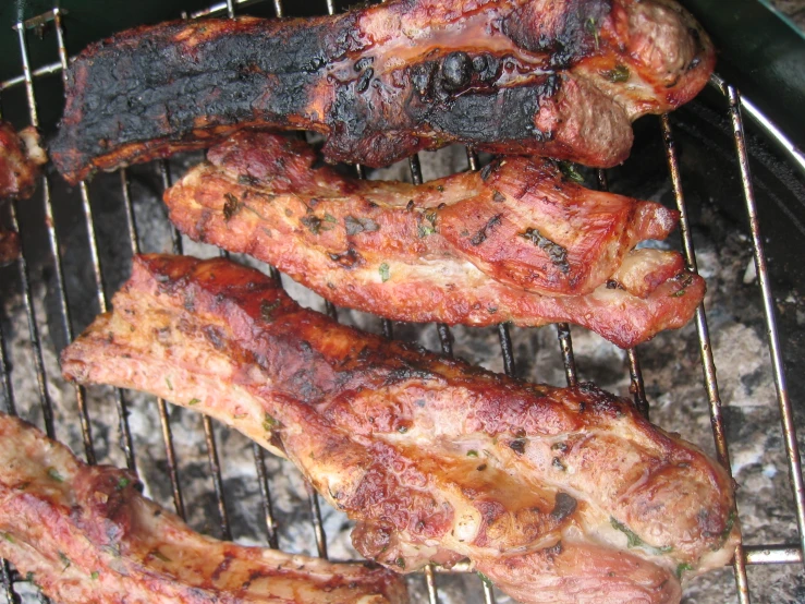 ribs are cooking on a grill with one being cooked