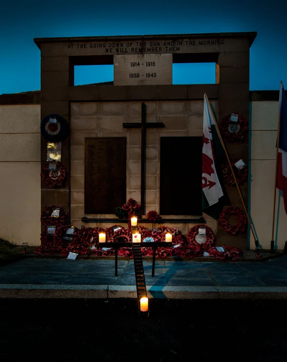a lit cross in front of a building decorated with candles