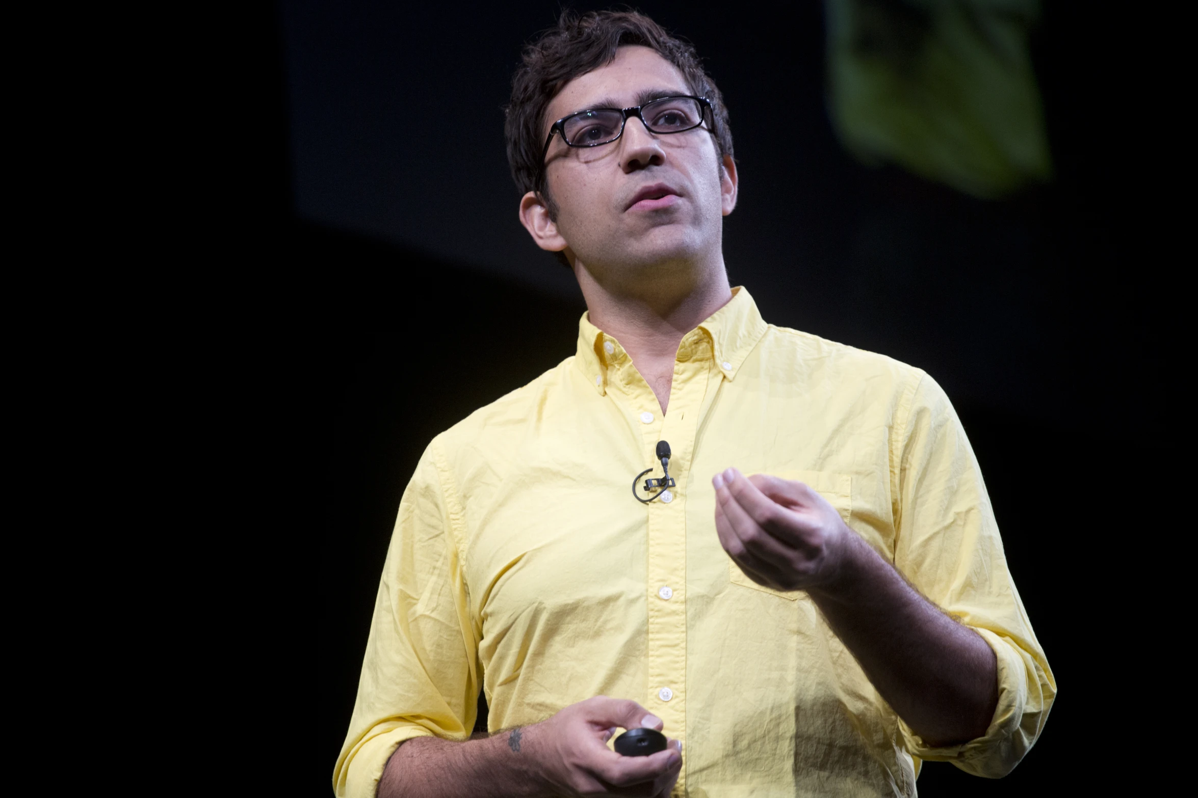 a man in glasses speaking into microphone while standing