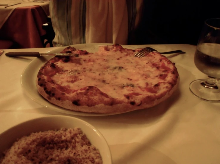 a plate with a pizza and bowl of grated potatoes