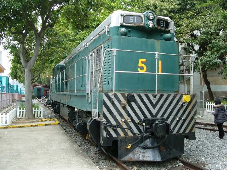 the green train car is on display at the rail road track