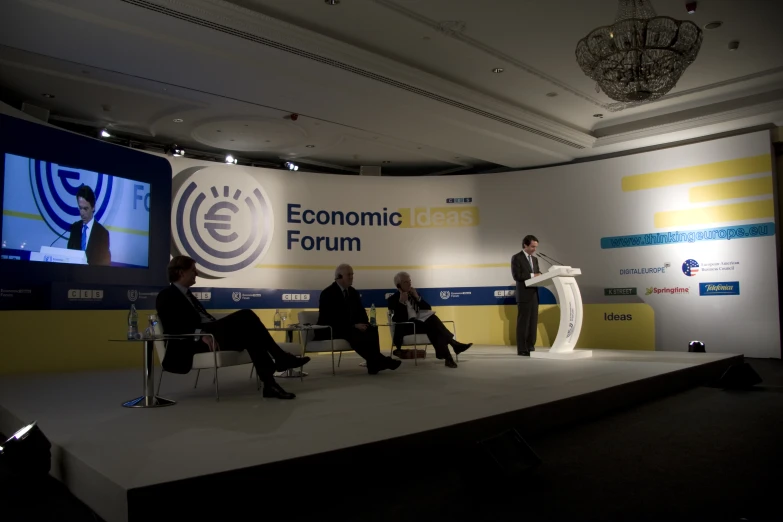 three people are standing in front of a microphone at an economic forum