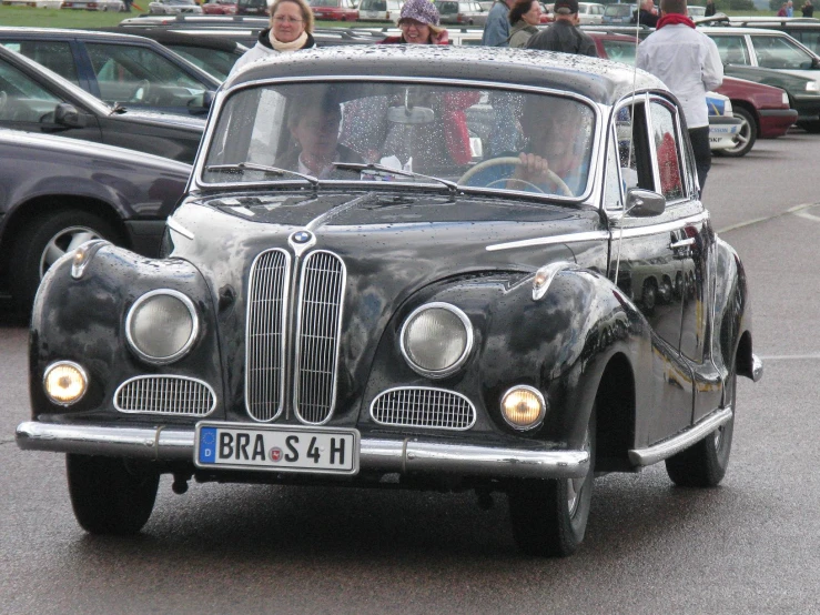 an old vintage classic car with people standing around