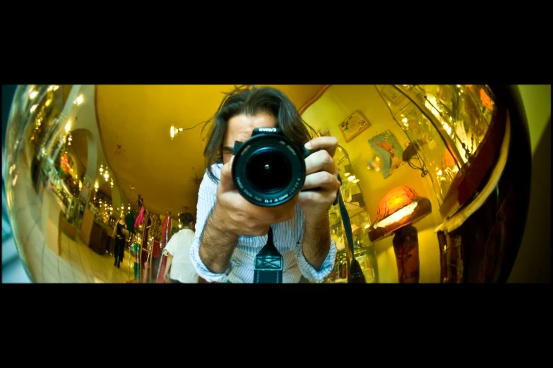 a young man holding a camera in a very high perspective