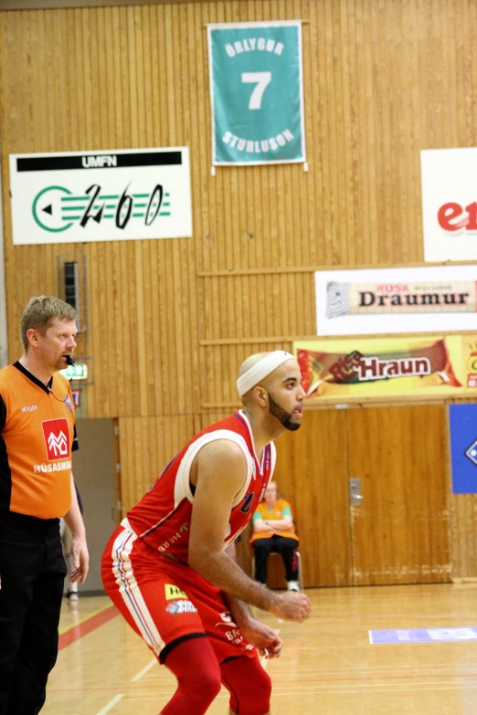 a basketball player walking down a court while wearing a white head band