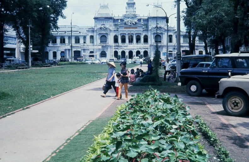 people walking in front of a large white mansion