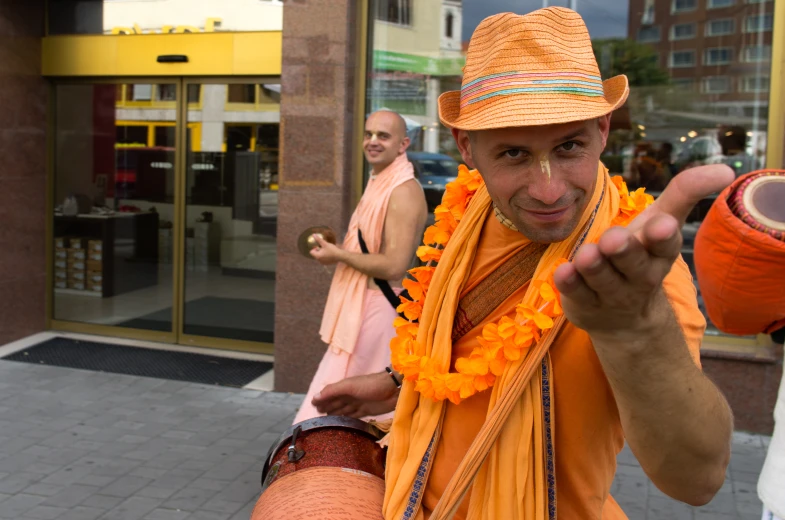 a man wearing a lei pointing with an orange frisbee