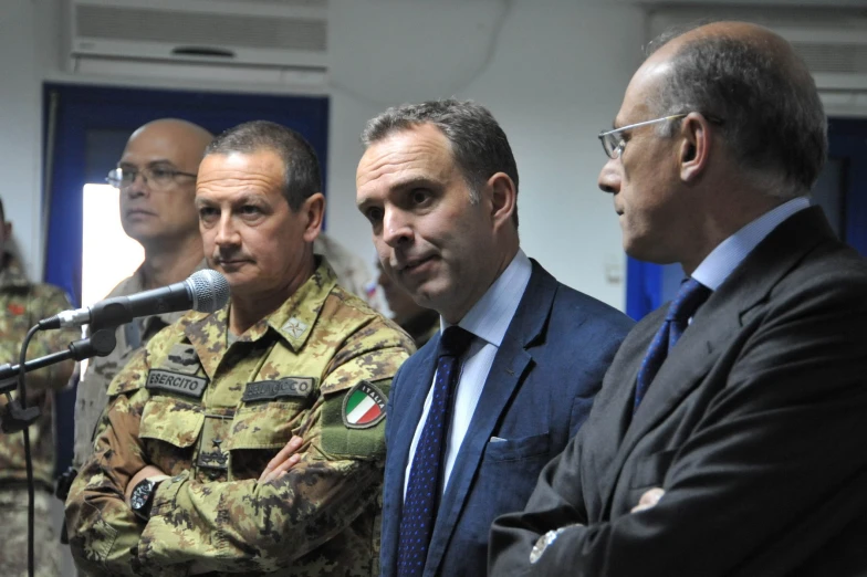 three men are standing at the microphone in front of some military personnel