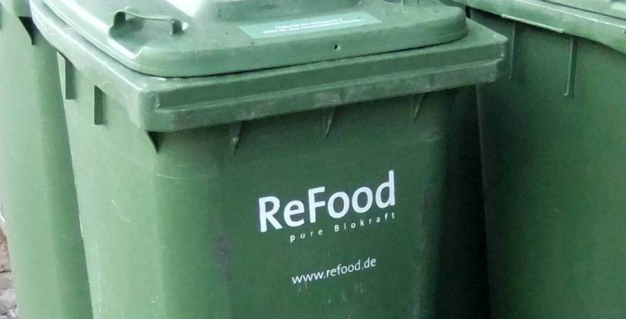 two green garbage cans are stacked next to each other