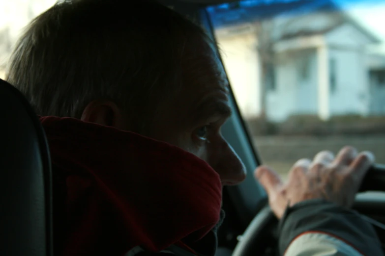 a man driving in a car with another person in front of him