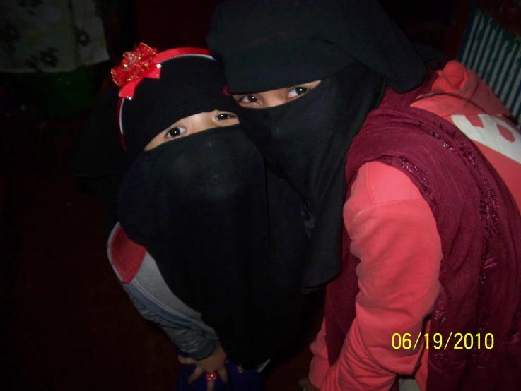 two girls are posing with black head coverings